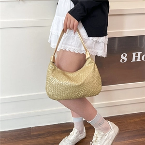 Chic metallic gold hobo bag with woven texture worn as a stylish underarm shoulder bag