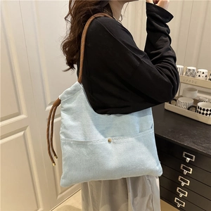 Light blue denim tote bag with brown woven straps and spacious outer pocket