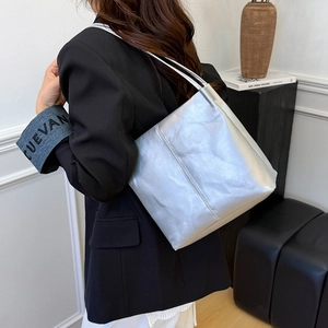 Silver metallic tote bag shown on shoulder of model in black suit for chic urban style