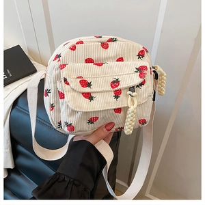 Detail view of cream corduroy fabric with cute strawberry prints on a mini crossbody bag