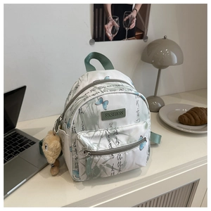 Close-up of mini backpack showing green bamboo leaves, blue butterfly, and calligraphy art