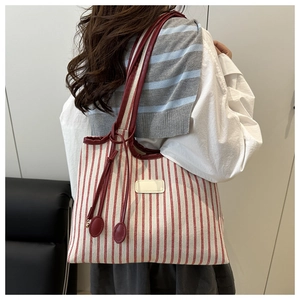 Détail du cabas à rayures rouges et blanches avec bandoulière en cuir et pendentif perlé rouge