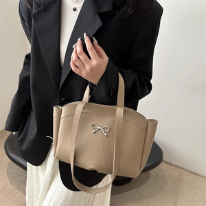 Elegant beige PU leather basket bag with silver bow accent, styled with fashion outfit