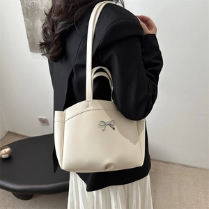 Minimalist off-white leather bucket bag with silver bow buckle and adjustable strap