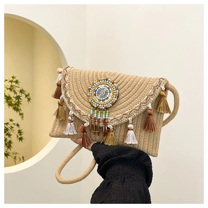 Dettaglio borsa di paglia bohémien con nappe colorate e ricami in stile etnico