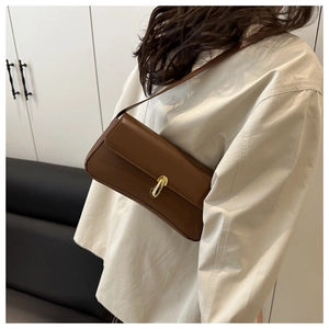 Detailed view of brown minimalist shoulder bag with golden metal turn-lock and slim strap