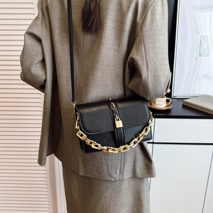 Chic black matte square crossbody bag with gold chain and leather strap on a blazer