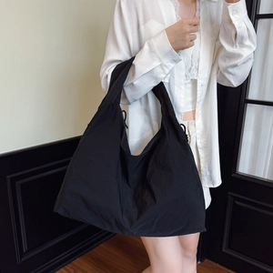 Grand sac cabas noir en toile pour femme avec cordon de serrage porté par un mannequin