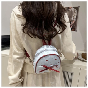 Mini white backpack with red bows and heart charm worn by model for daily outfit style