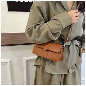 Detail of a brown rectangular crossbody bag with elegant stitching on a model's outfit