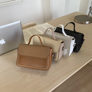 Detail view of stylish crossbody bags in four colors on a desk with woven leather textures