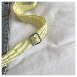 Detail of adjustable light yellow woven shoulder strap with silver metal buckle on bag
