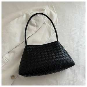Detailed view of the black woven leather texture and trapezoidal design of the handbag
