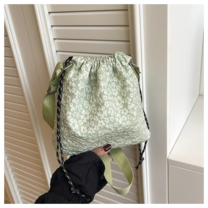 Detail view of mint green drawstring bucket bag with white floral jacquard texture