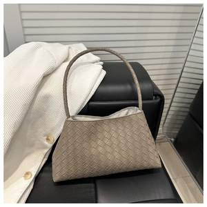 Close-up of premium light brown intrecciato woven leather tote on a black leather chair