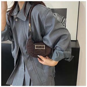 Close-up of a dark brown crocodile texture half-moon bag with gold wavy hardware