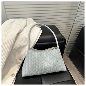 Close-up of light blue woven handbag with premium rhombus weave and cylindrical handle