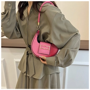 Detailed close-up of pink croc-embossed crescent shoulder bag with golden metal buckle