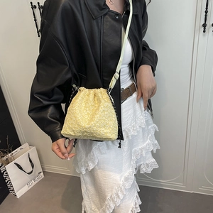 Floral drawstring bucket bag in yellow with adjustable strap shown on model shoulder