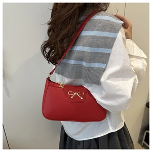 Detail of red bow underarm bag showing lychee grain leather and gold metal hardware