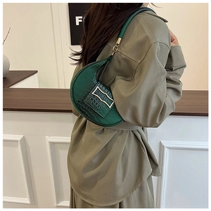 Fashionable emerald green crescent shoulder bag with crocodile pattern on a model