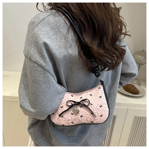 Pink bow underarm bag with relief texture and heart pendant worn on shoulder