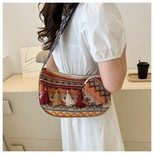 Detail of bohemian woven crossbody bag with ethnic patterns and colorful tassels