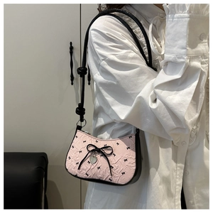 Detail of pink bow shoulder bag with embossed texture and heart-shaped metal pendant charm