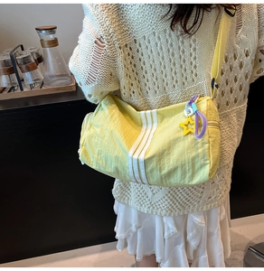 Detail of yellow nylon cylinder bag featuring white stripes and adjustable strap