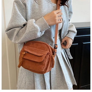 Detailed texture of brown corduroy crossbody bag with woven zipper pull detail