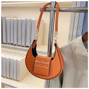 Close-up of bright orange faux crocodile skin texture and gold metal buckle on handbag