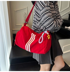 Macro detail of large red canvas tote bag with white stripes and star charm accessory