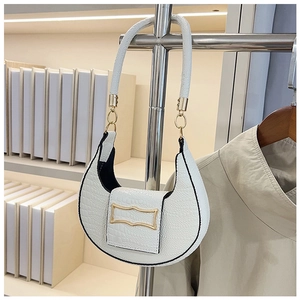Detail of cream crescent shoulder bag featuring crocodile pattern and gold hardware