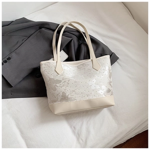 Detail of white tote bag featuring gray butterfly patterns and leather reinforced bottom