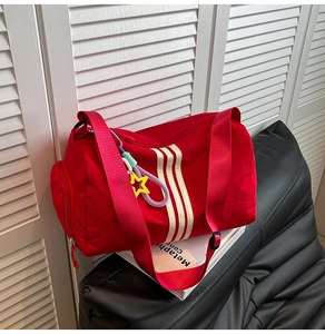 Detail of red waterproof nylon gym bag with white stripes and star pendant decoration