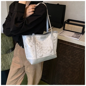 Detailed view of silver tote bag with butterfly prints and fashion label on shoulder