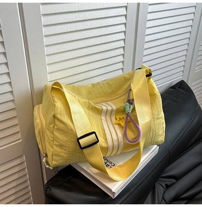 Macro detail of yellow nylon tote bag with white stripes and star charm on leather sofa