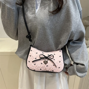 Pink underarm bag with black bows, pleated design, and heart-shaped charm strap