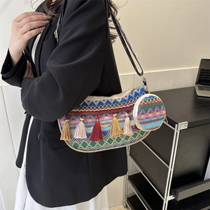 Ethnic bohemian woven bucket bag with tassel accents and broad leather shoulder strap