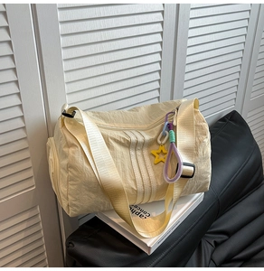 Detail of creamy yellow nylon tote bag with star charm and wide shoulder strap