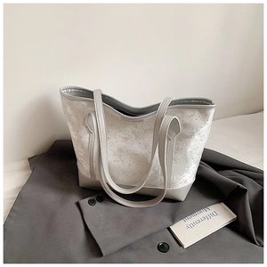 Detail showing white beaded floral print and grey leather base of the fashion tote bag
