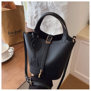 Close-up of black lychee grain leather bucket bag with gold hardware and smiley tag