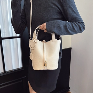 Chic cream-colored leather bucket bag with top handle and shoulder strap for women