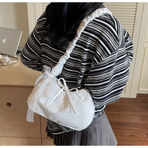 Close-up of white floral lace shoulder bag with pleated straps and bow detail
