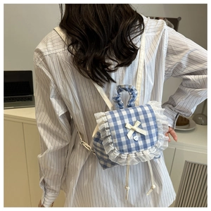 Detail showing blue gingham mini backpack with lace trim and heart button on a model