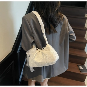 Detail of white lace shoulder bag with floral patterns, bow accents, and ruffled straps