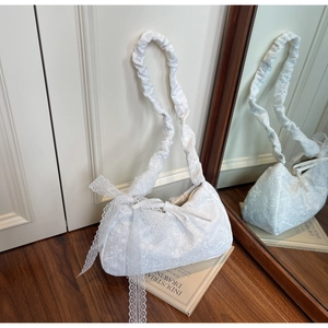 Close-up of white lace embroidery texture and ribbon bow on minimalist shoulder bag
