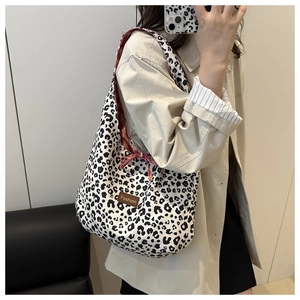 Detailed close-up of a leopard print canvas tote bag featuring a brown leather fashion tag