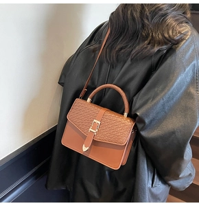 Detail of camel brown crossbody bag with crocodile pattern embossed flap and metal buckle