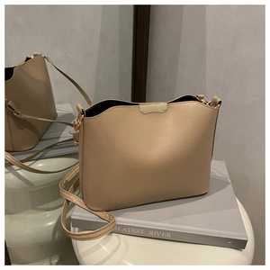 Detail view of the khaki bucket bag with smooth leather texture and golden metal accents